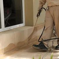 General pest control technician spraying exterior perimeter around a home in Jackson, MS