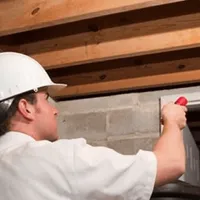 Termite inspection technician checking a basement wall and framing for termite activity in Jackson, MS
